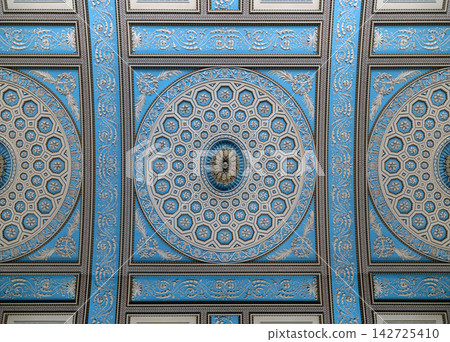 an ornately decorated, neoclassical ceiling painted in a striking palette of powder blue and cream, featuring an intricate central medallion composed of concentric geometric patterns and gilded floral an ornately decorated, neoclassical ceiling painted in a striking palette of powder blue and cream, featuring an intricate central medallion composed of concentric geometric patterns and gilded floral 142725410