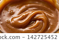 Extreme macro food photography highlighting the glossy, flowing swirl texture of rich golden caramel sauce. 142725452