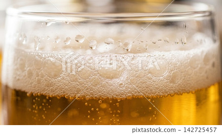 Extreme close up texture of a refreshing cold pint glass highlighting rising carbonation and amber liquid glow. Extreme close up texture of a refreshing cold pint glass highlighting rising carbonation and amber liquid glow. 142725457