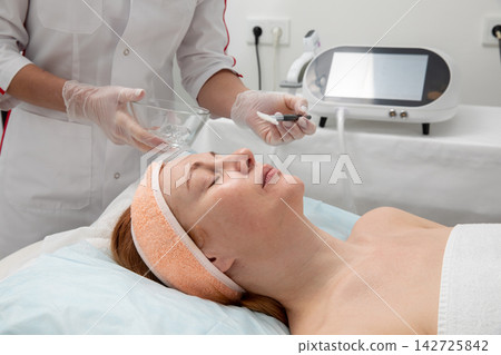 Cosmetologist Applying Cosmetic Gel to Woman Face with Brush During Skincare Treatment Cosmetologist Applying Cosmetic Gel to Woman Face with Brush During Skincare Treatment 142725842
