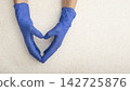 Caucasian hands in medical gloves showing heart shape gesture over flat table with copy space 142725876