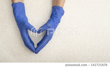 Caucasian hands in medical gloves showing heart shape gesture over flat table with copy space Caucasian hands in medical gloves showing heart shape gesture over flat table with copy space 142725876