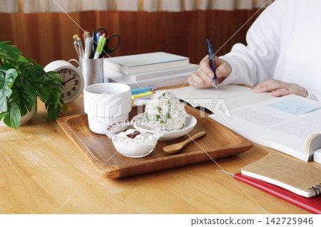 一個人一邊學習一邊吃著飯糰和優格當宵夜。 一個人一邊學習一邊吃著飯糰和優格當宵夜。 142725946