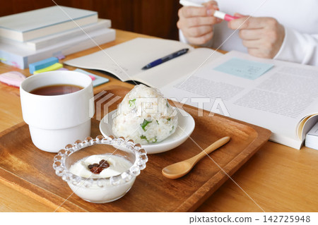 一個人一邊學習一邊吃著飯糰和優格當宵夜。 142725948