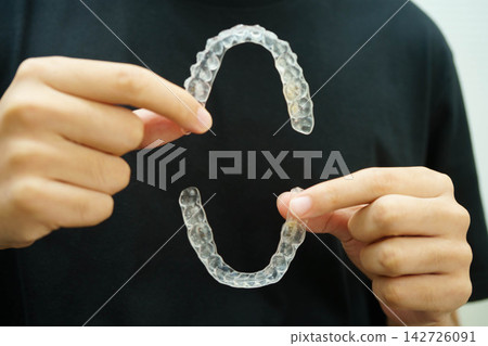 Man holding invisible aligner orthodontic retainer for dental teeth straightening. Man holding invisible aligner orthodontic retainer for dental teeth straightening. 142726091