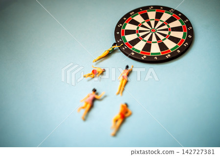 Miniature figurines of swimmers diving towards a dartboard on a blue background, showcasing a playful and creative concept of sports and leisure activities Miniature figurines of swimmers diving towards a dartboard on a blue background, showcasing a playful and creative concept of sports and leisure activities 142727381