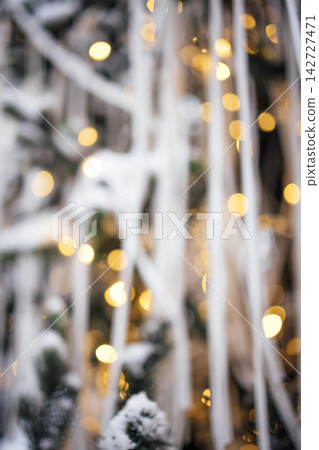 Softly blurred winter scene featuring snow-covered branches and warm glowing lights, creating a festive atmosphere with a bokeh effect in the background Softly blurred winter scene featuring snow-covered branches and warm glowing lights, creating a festive atmosphere with a bokeh effect in the background 142727471