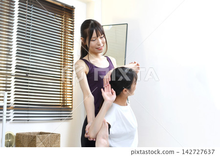Asian woman learns pigeon pose in yoga class Asian woman learns pigeon pose in yoga class 142727637