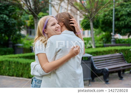 Happy teenage girl hugging mother warmly standing in park Happy teenage girl hugging mother warmly standing in park 142728028