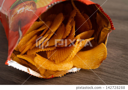 Bangkok, Thailand - May 15, 2022 Potato chips in open bag, delicious BBQ seasoning spicy for crips, thin slice deep fried snack fast food. Bangkok, Thailand - May 15, 2022 Potato chips in open bag, delicious BBQ seasoning spicy for crips, thin slice deep fried snack fast food. 142728288