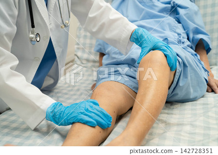 Doctor checking Asian elderly woman patient with scar knee replacement surgery in hospital. 142728351
