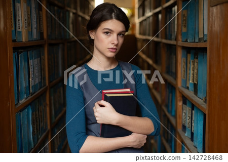 Young woman selecting book from library shelf. Young woman selecting book from library shelf. 142728468