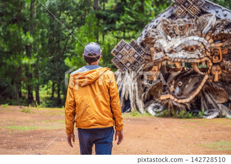 Man traveler visiting a large indigenous inspired sculpture installation near San Cristobal de las Casas Chiapas Mexico with outdoor art natural materials forest setting cultural identity and wide. Man traveler visiting a large indigenous inspired sculpture installation near San Cristobal de las Casas Chiapas Mexico with outdoor art natural materials forest setting cultural identity and wide. 142728510