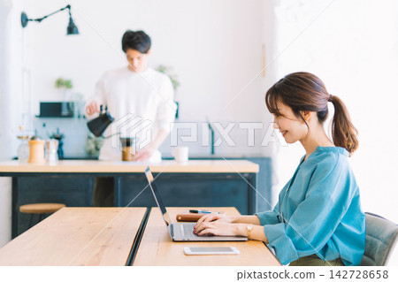 一名女子正在使用電腦，一名男子正在煮咖啡。 142728658