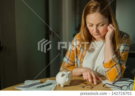 Cost of living crisis concept with worried woman counting coins at home, copy space Cost of living crisis concept with worried woman counting coins at home, copy space 142728701
