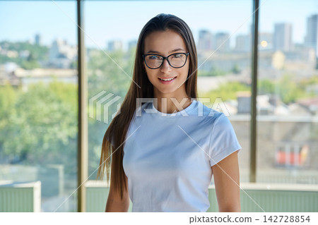Young smiling female student in eyeglasses looking directly at camera Young smiling female student in eyeglasses looking directly at camera 142728854