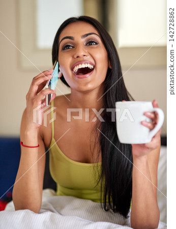 Indian woman, bed and happy for phone call in home with coffee for good news or conversation. Female person, bedroom and smile or excited for communication with cup in morning and laughing or fun Indian woman, bed and happy for phone call in home with coffee for good news or conversation. Female person, bedroom and smile or excited for communication with cup in morning and laughing or fun 142728862