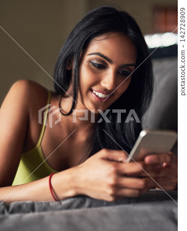 Smile, rest and Indian girl with phone, typing and relax in living room, sofa and chat on social media. Communication, texting and woman with mobile, online and app with internet for person in home Smile, rest and Indian girl with phone, typing and relax in living room, sofa and chat on social media. Communication, texting and woman with mobile, online and app with internet for person in home 142728909