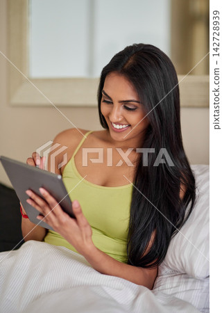 Indian woman, bed and smile with tablet in home for browsing internet for social media or entertainment. Stylus pen, bedroom and happy on website for online booking or applications in morning Indian woman, bed and smile with tablet in home for browsing internet for social media or entertainment. Stylus pen, bedroom and happy on website for online booking or applications in morning 142728939