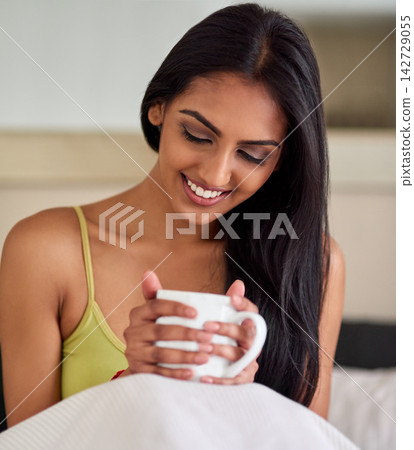 Indian woman, coffee and relax in bed with mug for happiness, resting or morning routine in bedroom. Smile, drink and person with hot beverage for enjoyment, stress relief or weekend break in home Indian woman, coffee and relax in bed with mug for happiness, resting or morning routine in bedroom. Smile, drink and person with hot beverage for enjoyment, stress relief or weekend break in home 142729055