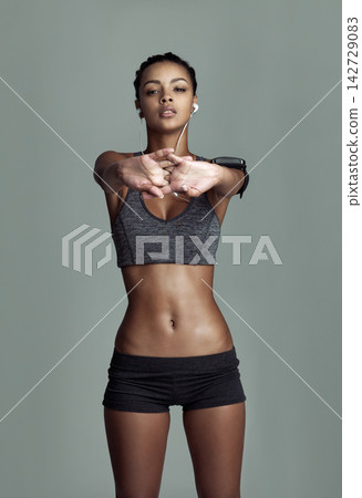 Studio portrait, woman and stretching for exercise with earphones, streaming kpop music and muscle warm up. Athlete girl, stretch arms and listen sound by gray background for start workout and audio Studio portrait, woman and stretching for exercise with earphones, streaming kpop music and muscle warm up. Athlete girl, stretch arms and listen sound by gray background for start workout and audio 142729083