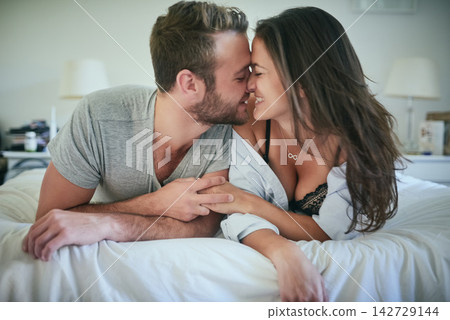 Romance, affection and couple in bed with kiss, love and morning bonding in apartment. Relationship, man and woman in bedroom with intimate embrace, passion or relax with happiness on weekend in home Romance, affection and couple in bed with kiss, love and morning bonding in apartment. Relationship, man and woman in bedroom with intimate embrace, passion or relax with happiness on weekend in home 142729144