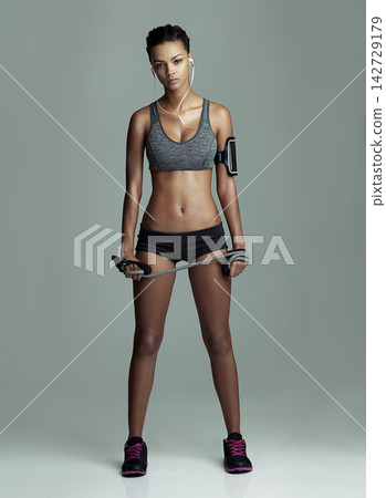 Body, jump rope and music with portrait of woman in studio isolated on gray background. Exercise, skipping and workout with serious athlete training for fitness challenge, health or performance Body, jump rope and music with portrait of woman in studio isolated on gray background. Exercise, skipping and workout with serious athlete training for fitness challenge, health or performance 142729179