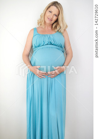 Pregnant, woman and hands on stomach in portrait for family, healthy mama with love in studio. Female person, holding or belly for pregnancy with white background for wellness, gratitude in Chicago 142729610