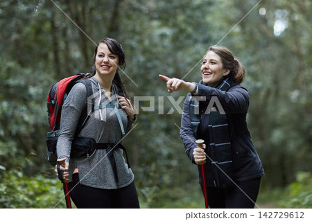 Women, backpack and gear while hiking in nature for fitness, wellness and health with conversation. Friends, speaking and smiling on mountain forest for exercise, workout and trekking with adventure Women, backpack and gear while hiking in nature for fitness, wellness and health with conversation. Friends, speaking and smiling on mountain forest for exercise, workout and trekking with adventure 142729612