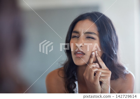 Frustrated, woman and face with hand for pimple popping in mirror reflection for skincare, grooming and morning routine. Indian, female person and dermatology with acne cleaning and facial breakout Frustrated, woman and face with hand for pimple popping in mirror reflection for skincare, grooming and morning routine. Indian, female person and dermatology with acne cleaning and facial breakout 142729614