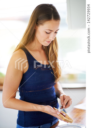 Woman, breakfast and kitchen with spread and toast, sandwich or food or bread. House, nutrition or wellness for hungry female person for snack, lunch or cooking or preparation or knife for ingredient 142729934