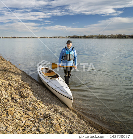 senior male paddler with expedition decked canoe on a lake shore in early spring, Boedecker Reservoir in northern Colorado senior male paddler with expedition decked canoe on a lake shore in early spring, Boedecker Reservoir in northern Colorado 142730027