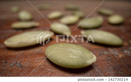 pile of pumpkin seeds on a weathered wood, macro shot with a probe lens 142730214