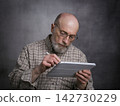 casual portrait of bald, bearded senior man working on a digital tablet with electronic pencil 142730229
