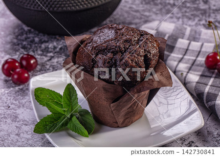 Chocolate muffin with mint and cherries on white plate Chocolate muffin with mint and cherries on white plate 142730841