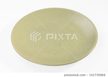 Olive green ceramic plate with subtle crackle glaze texture on clean white background, minimalist tableware design Olive green ceramic plate with subtle crackle glaze texture on clean white background, minimalist tableware design 142730968