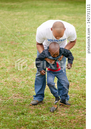 Man, volunteer and child in playing for charity in park, help and support by working as community service. Male person, kid and care with kindness for orphan, together and growth of development Man, volunteer and child in playing for charity in park, help and support by working as community service. Male person, kid and care with kindness for orphan, together and growth of development 142731111