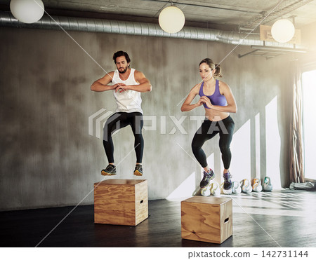 Jump, workout and couple in gym with box, power and training at fitness challenge together. Man, woman and personal trainer with balance, muscle development and healthy body exercise at sports club Jump, workout and couple in gym with box, power and training at fitness challenge together. Man, woman and personal trainer with balance, muscle development and healthy body exercise at sports club 142731144