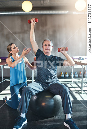Personal trainer, workout and senior man with dumbbell in clinic for physiotherapy, support or exercise. Fitness, female coach and elderly patient on ball for help, balance strength or rehabilitation Personal trainer, workout and senior man with dumbbell in clinic for physiotherapy, support or exercise. Fitness, female coach and elderly patient on ball for help, balance strength or rehabilitation 142731377