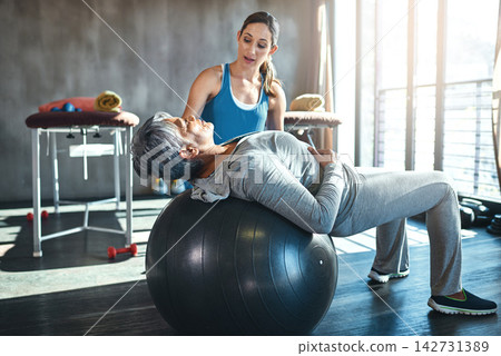 Exercise, physiotherapist and elderly woman with ball in clinic for rehabilitation, support or stretching. Injury, healthcare worker and senior patient for balance, recovery help or physical therapy Exercise, physiotherapist and elderly woman with ball in clinic for rehabilitation, support or stretching. Injury, healthcare worker and senior patient for balance, recovery help or physical therapy 142731389