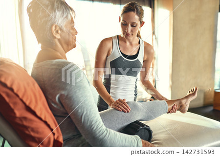 Stretching legs, physiotherapist and senior woman in clinic for rehabilitation, support or muscle pain. Healthcare, female coach and elderly patient for help, wellness training or physiotherapy Stretching legs, physiotherapist and senior woman in clinic for rehabilitation, support or muscle pain. Healthcare, female coach and elderly patient for help, wellness training or physiotherapy 142731593