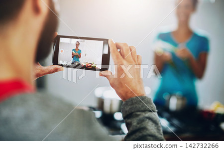 People, cooking and video with phone in kitchen for photography of woman with healthy food. Film, chef and person live streaming with nutrition, diet and screen with nutritionist in home vlog People, cooking and video with phone in kitchen for photography of woman with healthy food. Film, chef and person live streaming with nutrition, diet and screen with nutritionist in home vlog 142732266