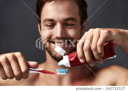 Brushing teeth, hands and smile with man in studio isolated on blue background for dental care. Toothbrush, toothpaste and product with happy person in bathroom, cleaning mouth for protection Brushing teeth, hands and smile with man in studio isolated on blue background for dental care. Toothbrush, toothpaste and product with happy person in bathroom, cleaning mouth for protection 142732527