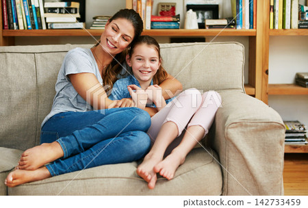 Portrait, mother and child on sofa with hug in living room for care, support or bonding on weekend. Family, relax and woman with girl in embrace at home for love, motherhood or connection to daughter 142733459