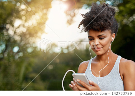 Fitness, black woman and cellphone with headset for listening music, podcast and radio with smile. Nature, female runner and mobile to change audio track, song and playlist for motivation outdoor Fitness, black woman and cellphone with headset for listening music, podcast and radio with smile. Nature, female runner and mobile to change audio track, song and playlist for motivation outdoor 142733789
