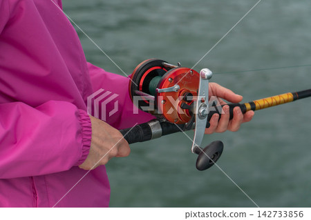 Close-up of hands holding fishing rod with reel during sea fishing trip. Recreational fishing, angling equipment, outdoor leisure, active travel, marine adventure and sport fishing Close-up of hands holding fishing rod with reel during sea fishing trip. Recreational fishing, angling equipment, outdoor leisure, active travel, marine adventure and sport fishing 142733856