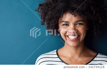 Black woman, portrait and smile with funny, glow and confident on blue studio background. Girl, face and model with afro laughing for joke, comic and happiness or positive mood with natural beauty Black woman, portrait and smile with funny, glow and confident on blue studio background. Girl, face and model with afro laughing for joke, comic and happiness or positive mood with natural beauty 142734128