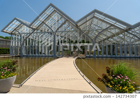 Walkway over a reflection pool to a modern glass conservatory Walkway over a reflection pool to a modern glass conservatory 142734307