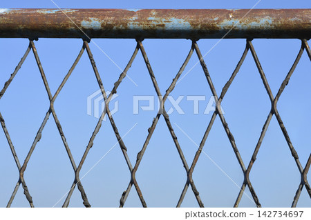 Weathered metal fence against a blue sky Weathered metal fence against a blue sky 142734697