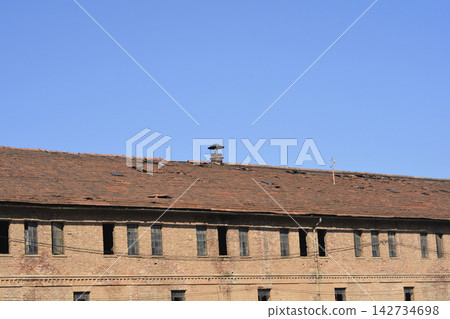 Old brick factory building with damaged clay tile roof Old brick factory building with damaged clay tile roof 142734698